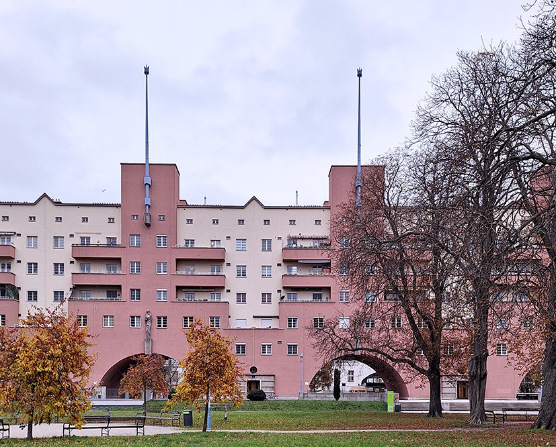 Ikonisches Motiv des Karl-Marx-Hofes die rosa gefärbten plastischen Bauteile mit Durchgängen vor hellem Hintergrund.